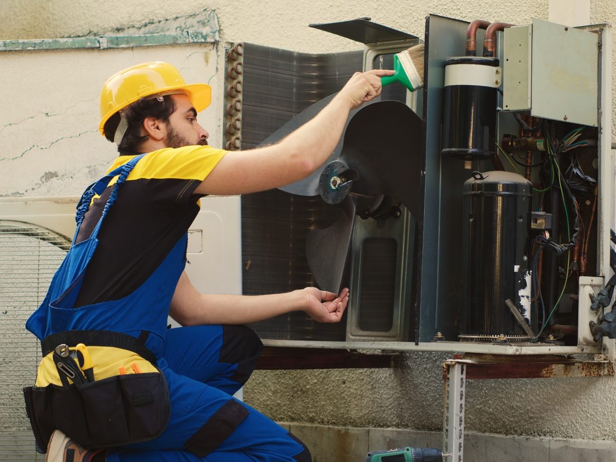 An HVAC technician servicing an outdoor condenser