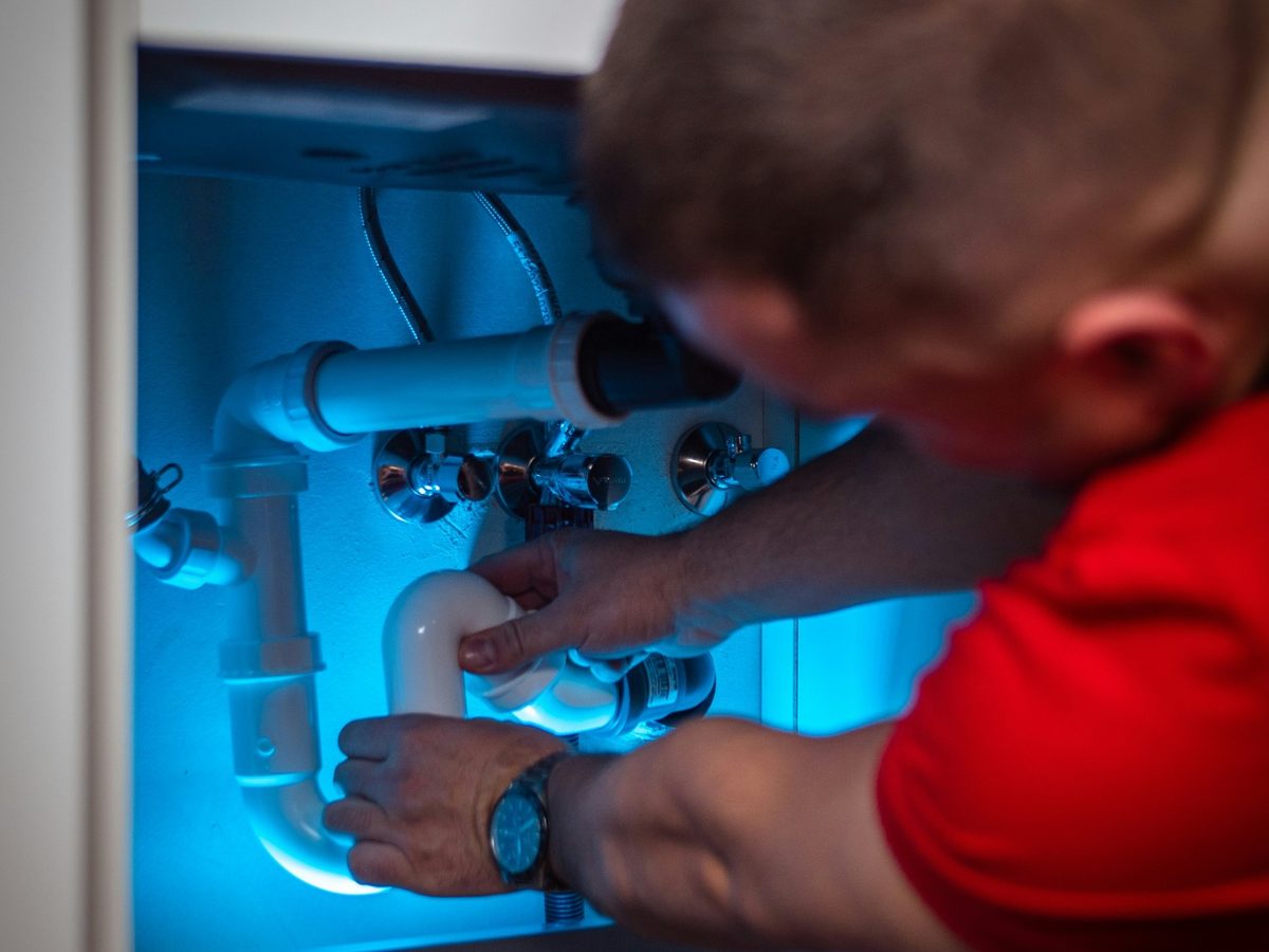 A plumber working on a trap under a sink