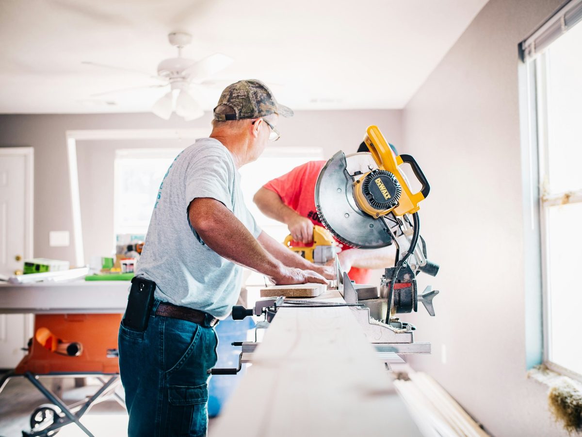 Two carpenters cutting trim on a mitre saw